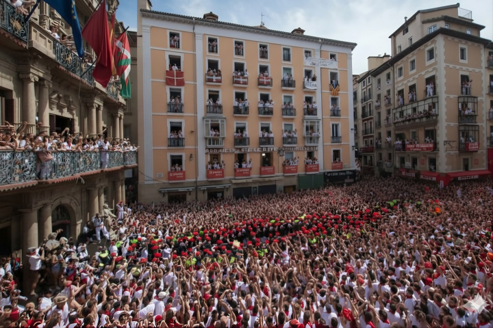 Large crowd in a square with people on balconies during a festival event.