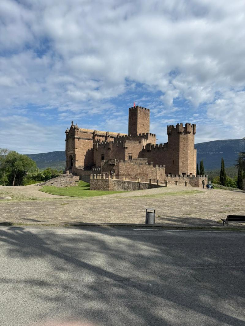 Stone castle with towers under a partly cloudy sky.