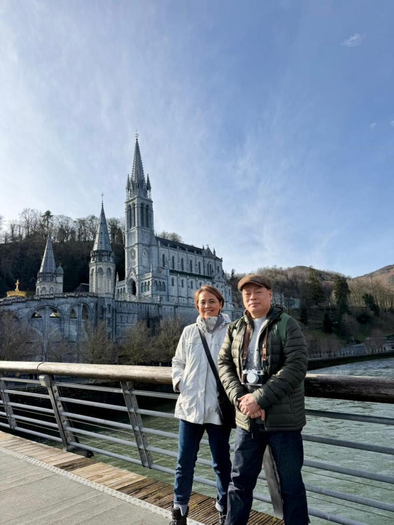 Two people standing on a bridge with a large church in the background.