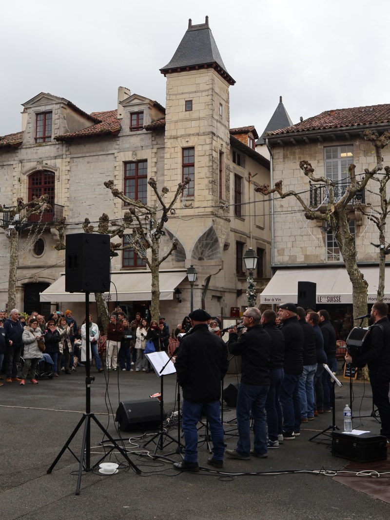 Outdoor choir performance in a European plaza with a crowd watching.