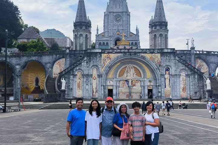 Group of six people posing in front of a historic church with tall spires.