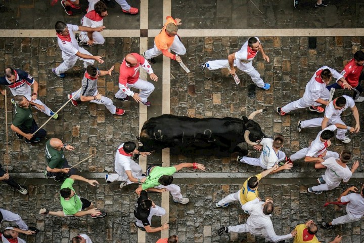 People running with a bull in a street during a festival.
