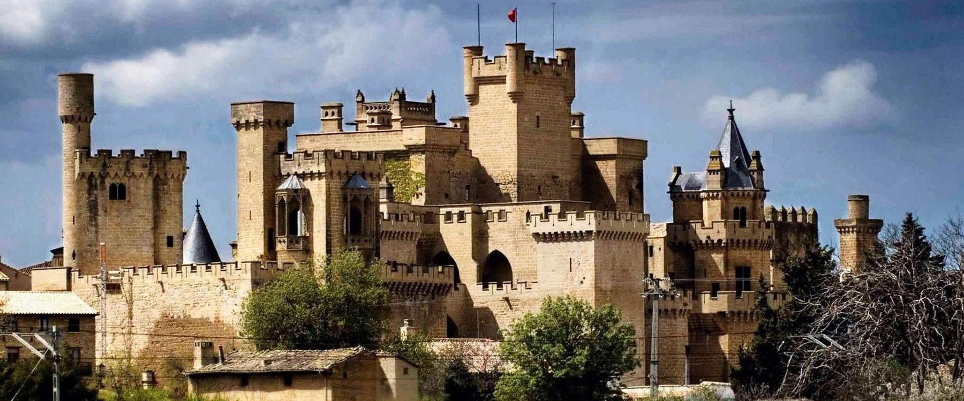 Medieval castle with turrets under a cloudy sky.