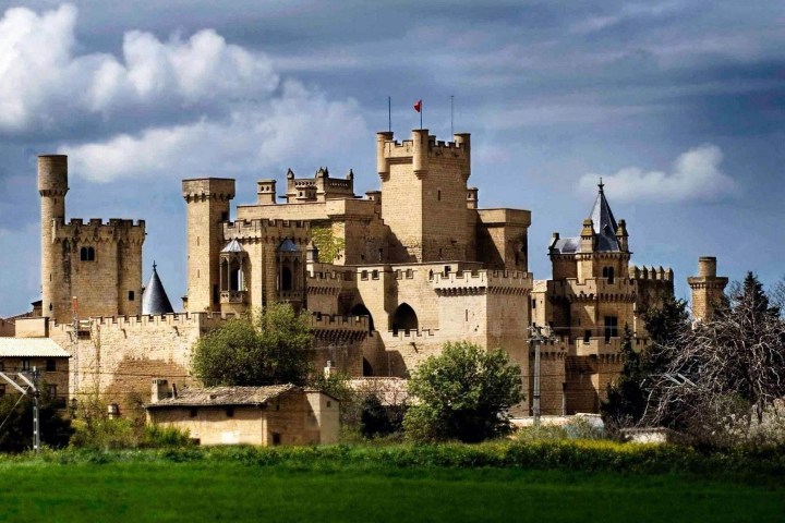 Medieval castle with turrets under a cloudy sky.