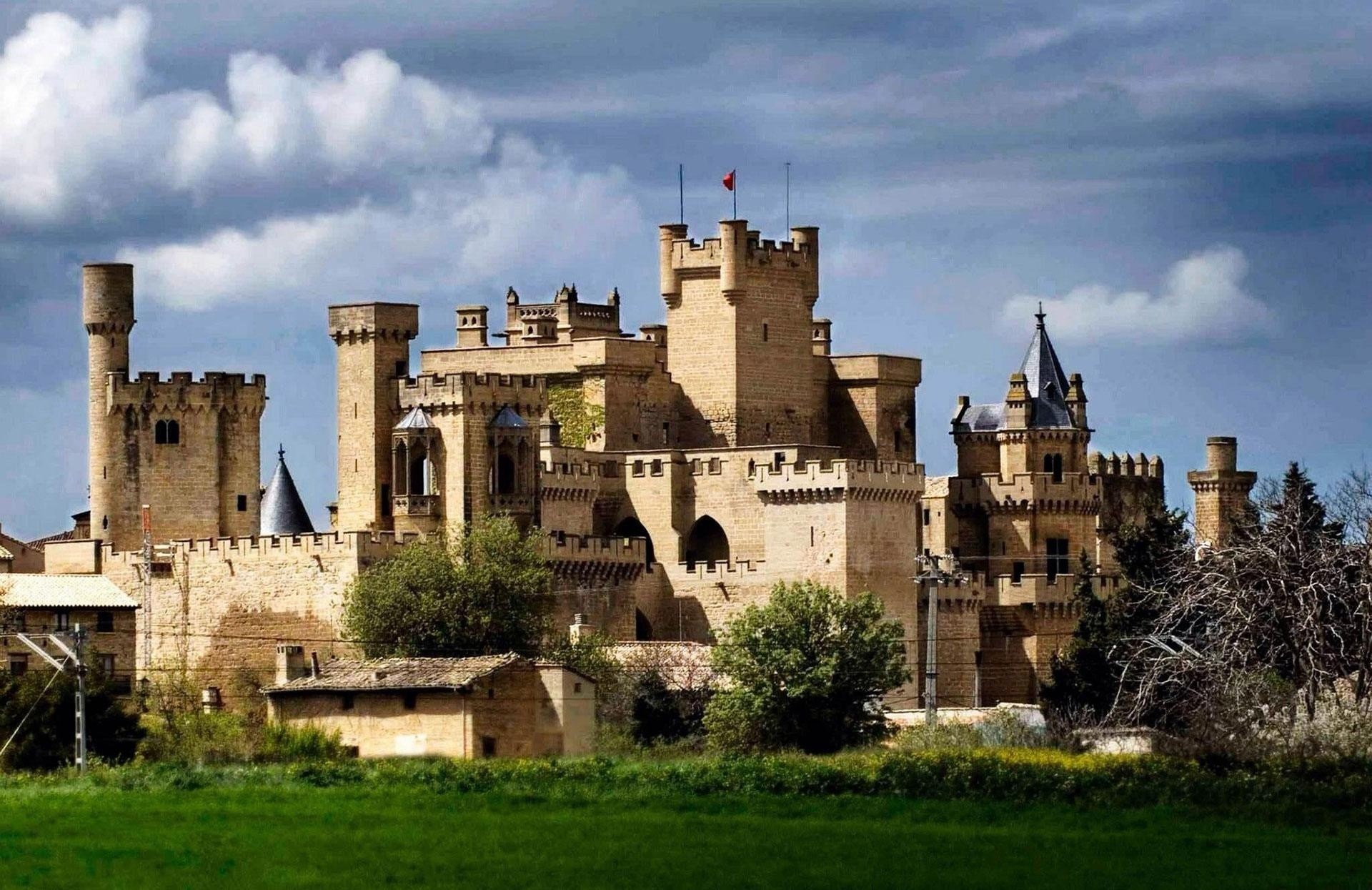 Medieval castle with turrets under a cloudy sky.